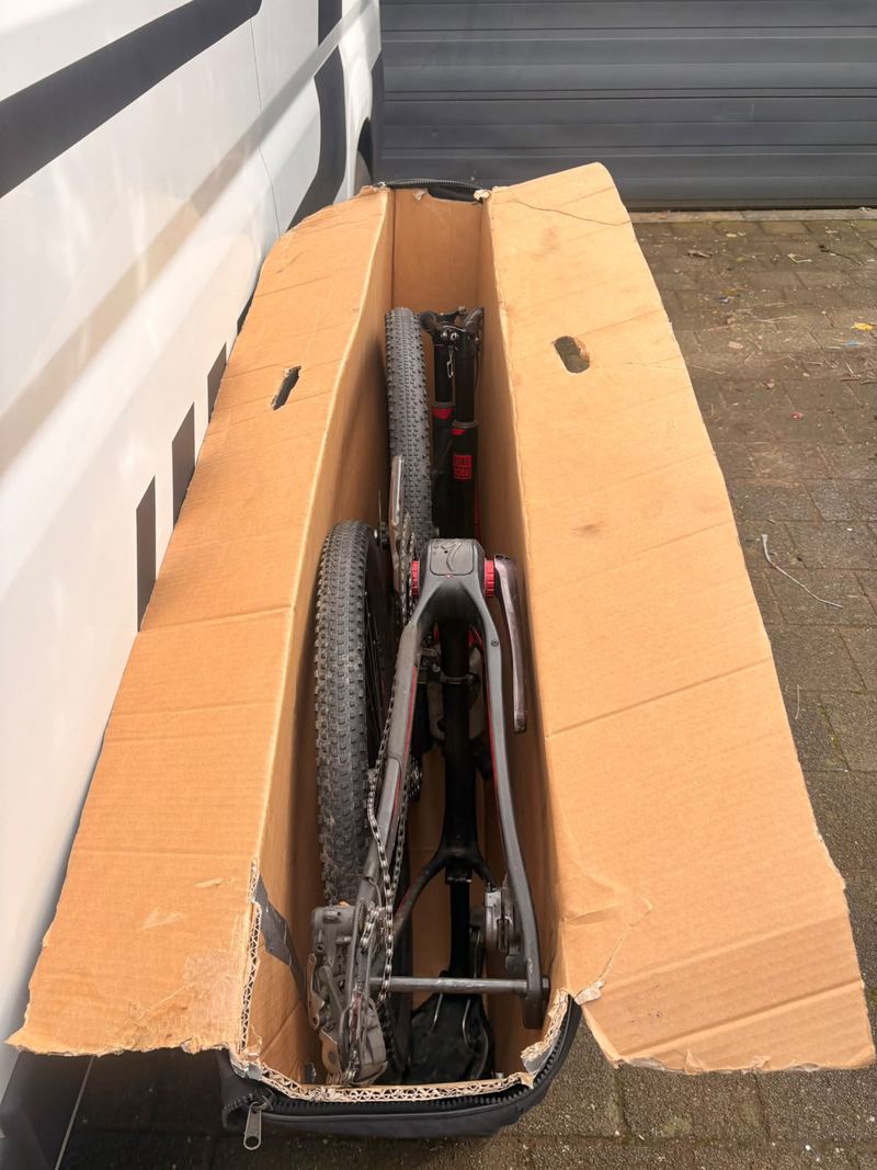 Fiets en wielen samen verpakt in een open kartonnen fietsdoos